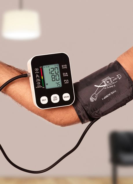 Digital blood pressure monitor with a blue arm cuff in the background